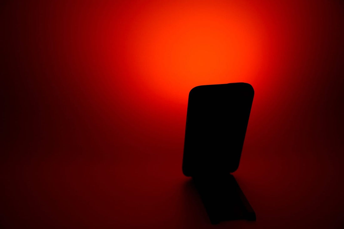 Halloween lights indoor: phone on a stand casting Flame Red light onto a dark wall