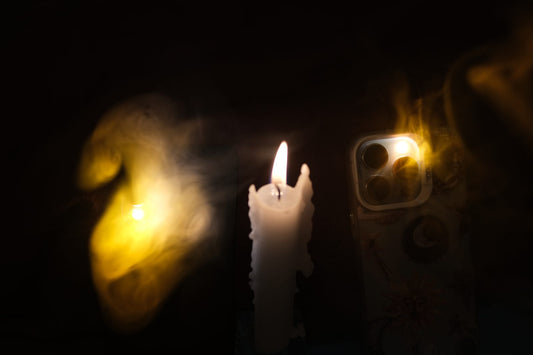 Phone with a warm gold Flashy Hue glow next to a burning candle – flameless candlelight