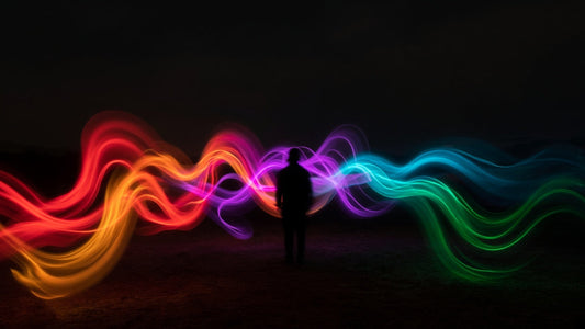 Light painting phone look: colourful light trails red to green in dark night, adult silhouette