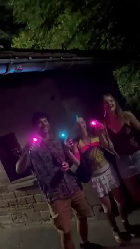 Three friends holding up phones with pink and blue light at night