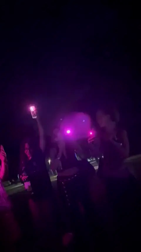 People in the dark with pink glowing phone flashlights
