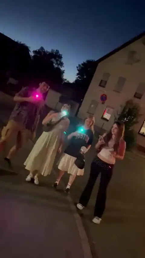 Friends walking down a street at dusk, phones glowing pink and turquoise