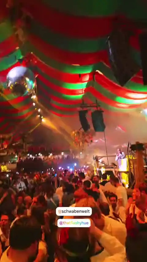 Crowd in a festival tent holding up phones with pink, green, blue and red light