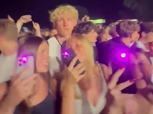 Festival crowd holding up phones with pink phone light
